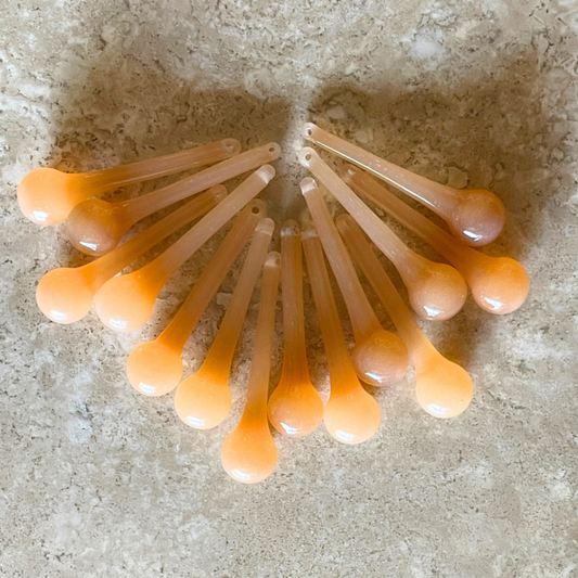 2 Sisters Artisan glass Set of 14 golden amber slightly opalescent opaque glass drops. These handmade gold glass raindrops are chameleons - really color shifting depending on the light source. (They look like creamy honey).